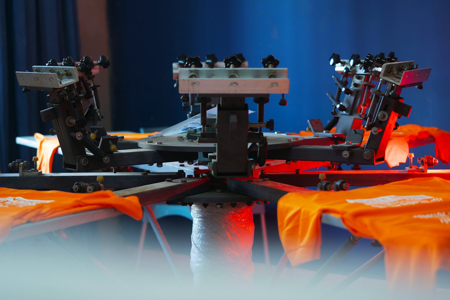 Orange T-Shirts auf einer Rundsiebdruckmaschine.